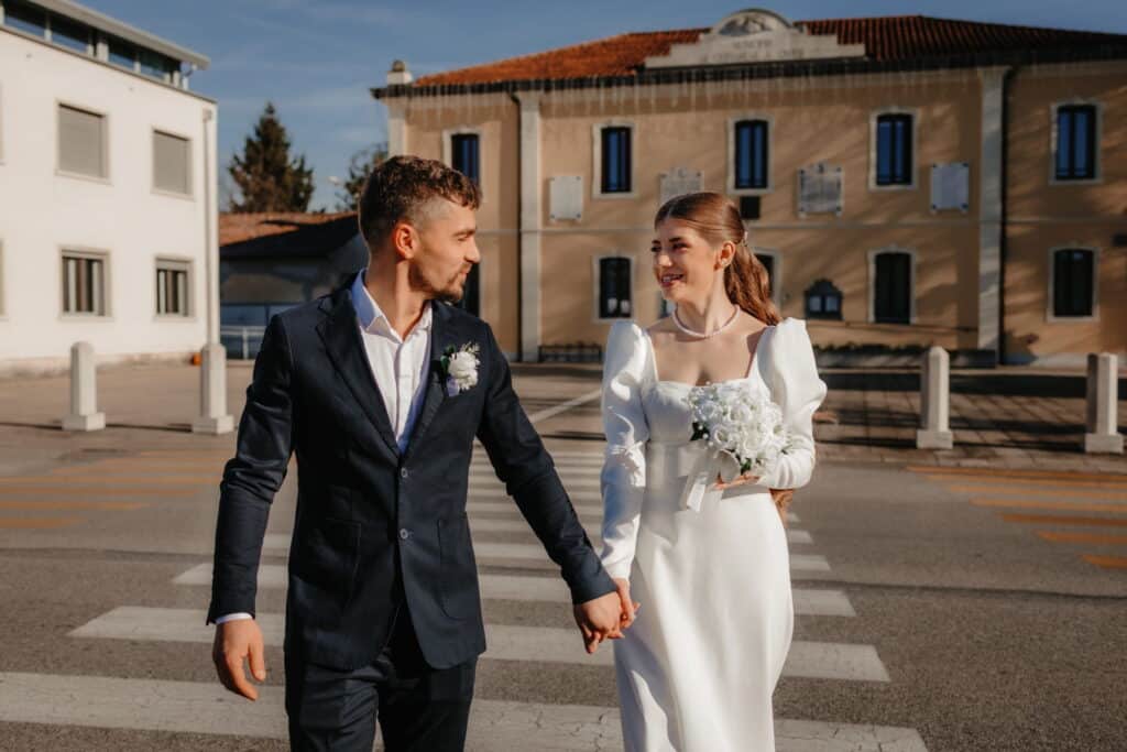 Scatto realizzato da un fotografo di matrimoni con una coppia che cammina mano nella mano dopo il matrimonio