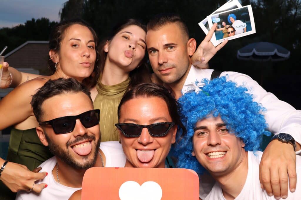 Ospiti che si divertono davanti al photobooth al matrimonio con gadget e sorrisi veri