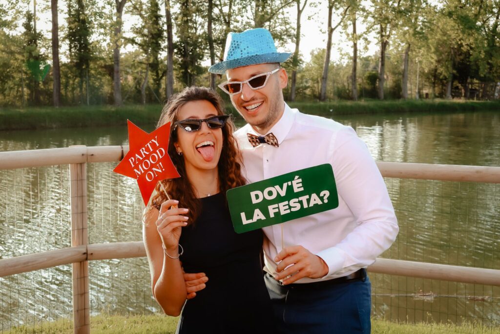 Coppia con cartelli divertenti al photo booth in riva al lago