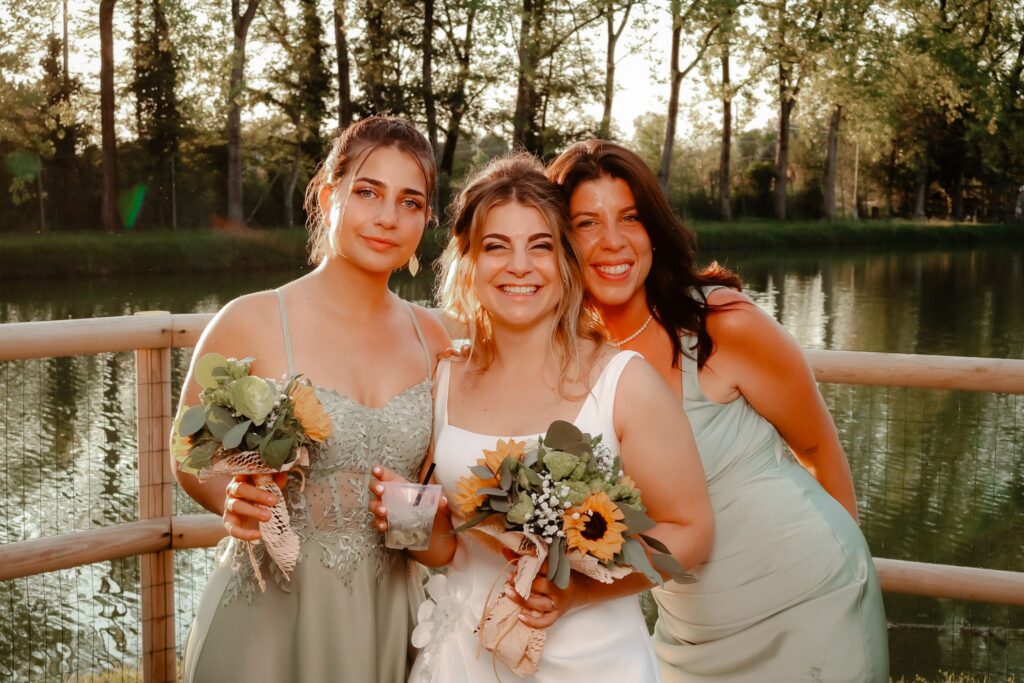 Sposa e damigelle con i bouquet in riva al lago