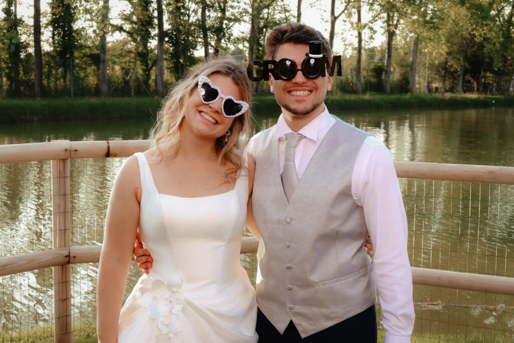 Sposi con occhiali a cuore al photo booth in riva al lago